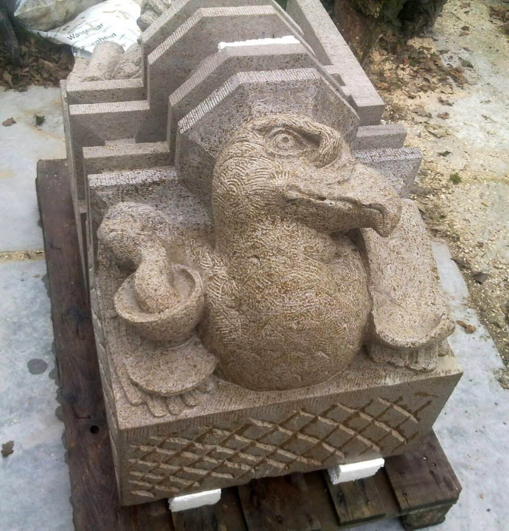 de kopie in Muschelkalk van een kraagsteen met de Adelaar van de evangelist Johannes.