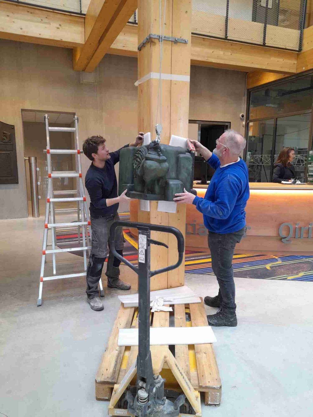 Koen van Velzen und Tim Kaarsemaker installieren einen Hahn aus Sandstein im Eingang des neuen Alliander-Gebäudes