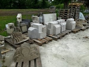 blokken voor nieuwe kraagstenen op het erf van de beeldhouwerij