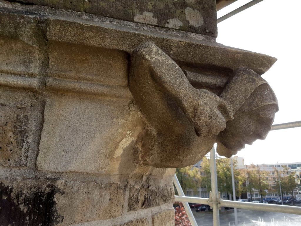 hoek ornament aan de Eusebiuskerk: Man die harlijnsmuts aan de punten vasthoudt