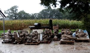 verweerde tufsteen beelden in opslag op erf beeldhowuerij